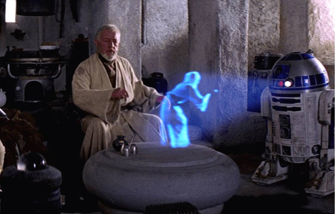 O robô R2D2 projeta um holograma, em cena de "Star Wars"