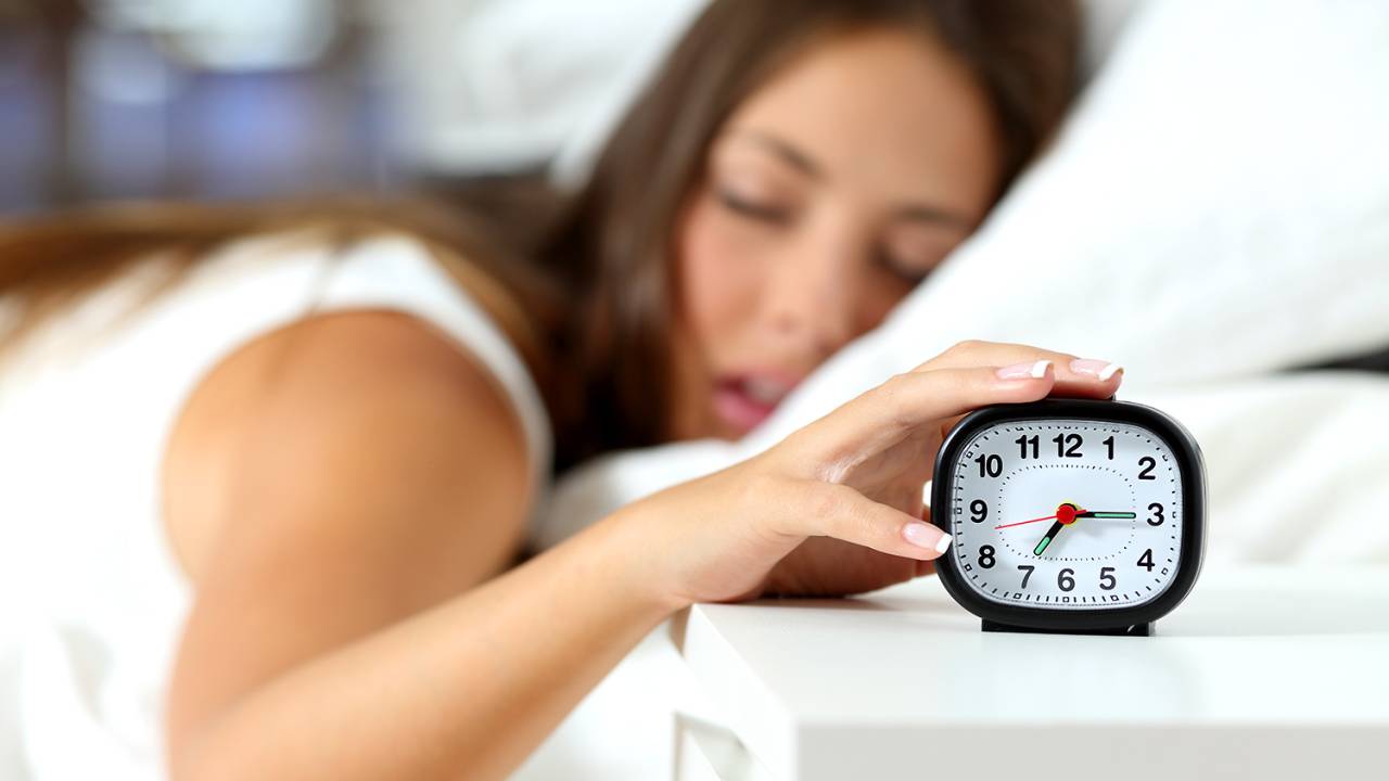 Mulher com sono desligando o despertador