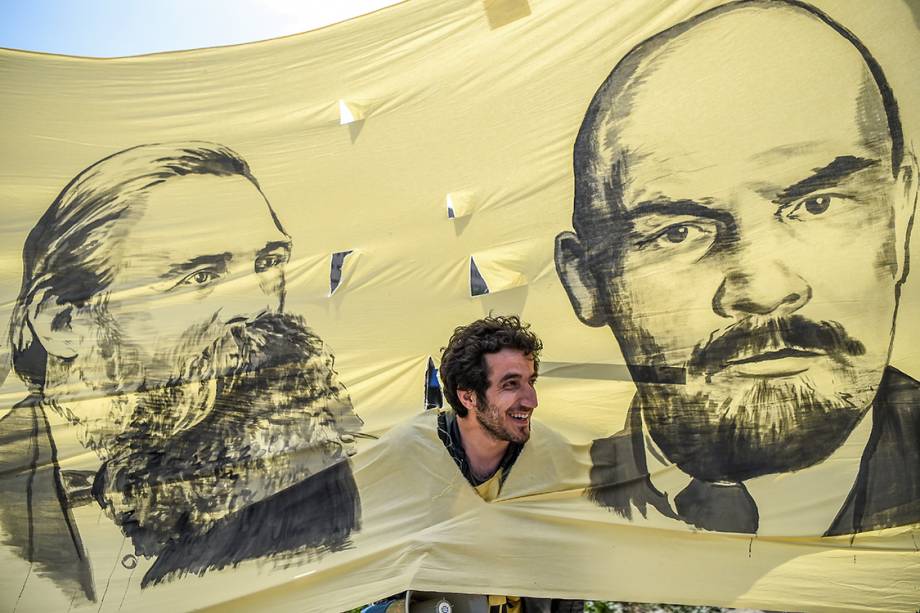 A man looks through the hole picturing German philosopher and communist thinker Friedrich Engels (L) and Soviet leader Vladimir Ilitch Lenin while he takes part in gather in Bakirkoy district as part of the the May Day rally, in Istanbul, on May 1, 2017. / AFP PHOTO / OZAN KOSE