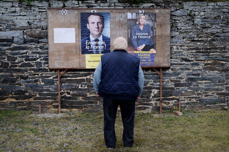 Homem observa cartazes dos candidatos perto de um local de votação durante o segundo turno das eleições presidenciais francesas na cidade rural de Saint-Sulpice-des-Landes - 07/05/2017 Homem observa cartazes dos candidatos perto de um local de votação durante o segundo turno das eleições presidenciais francesas na cidade rural de Saint-Sulpice-des-Landes - 07/05/2017