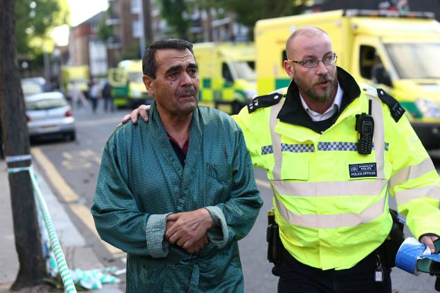 Um policial ajuda a evacuar a área próxima da tragédia ocorrida em Latimer Road, no oeste de Londres - 14/06/2017 Um policial ajuda a evacuar a área próxima da tragédia ocorrida em Latimer Road, no oeste de Londres - 14/06/2017