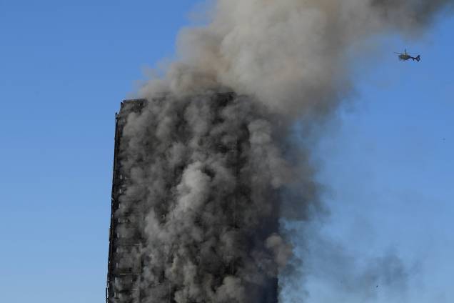 Helicóptero sobrevoa o Grenfell Tower após o fogo ter devastado boa parte do prédio - 14/06/2017 Helicóptero sobrevoa o Grenfell Tower após o fogo ter devastado boa parte do prédio - 14/06/2017