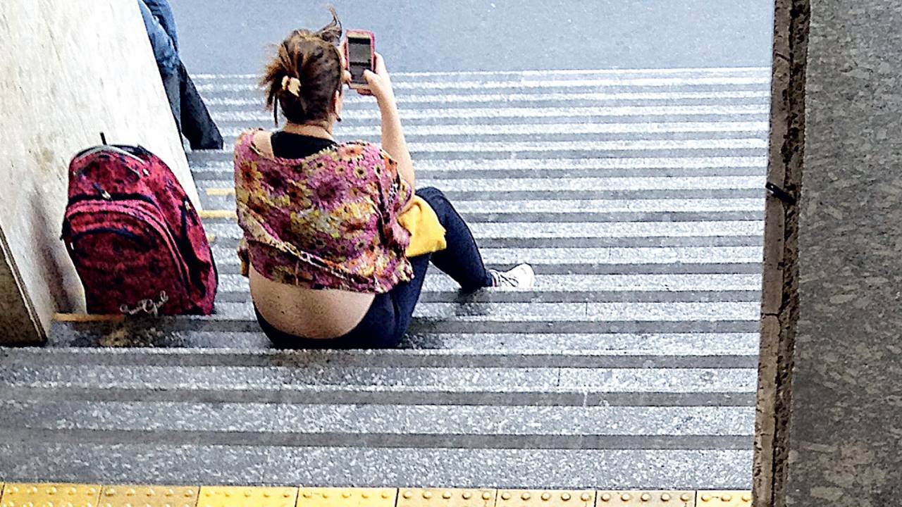 SOLIDÃO - Jovem nas escadarias do prédio de uma faculdade de São Paulo: alheia ao mundo lá fora, mas imersa nas redes sociais