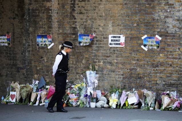 Uma policial vigia local onde pessoas deixam flores à vítima de atropelamento em Finsbury Park - 19/06/2017 Uma policial vigia local onde pessoas deixam flores à vítima de atropelamento em Finsbury Park - 19/06/2017
