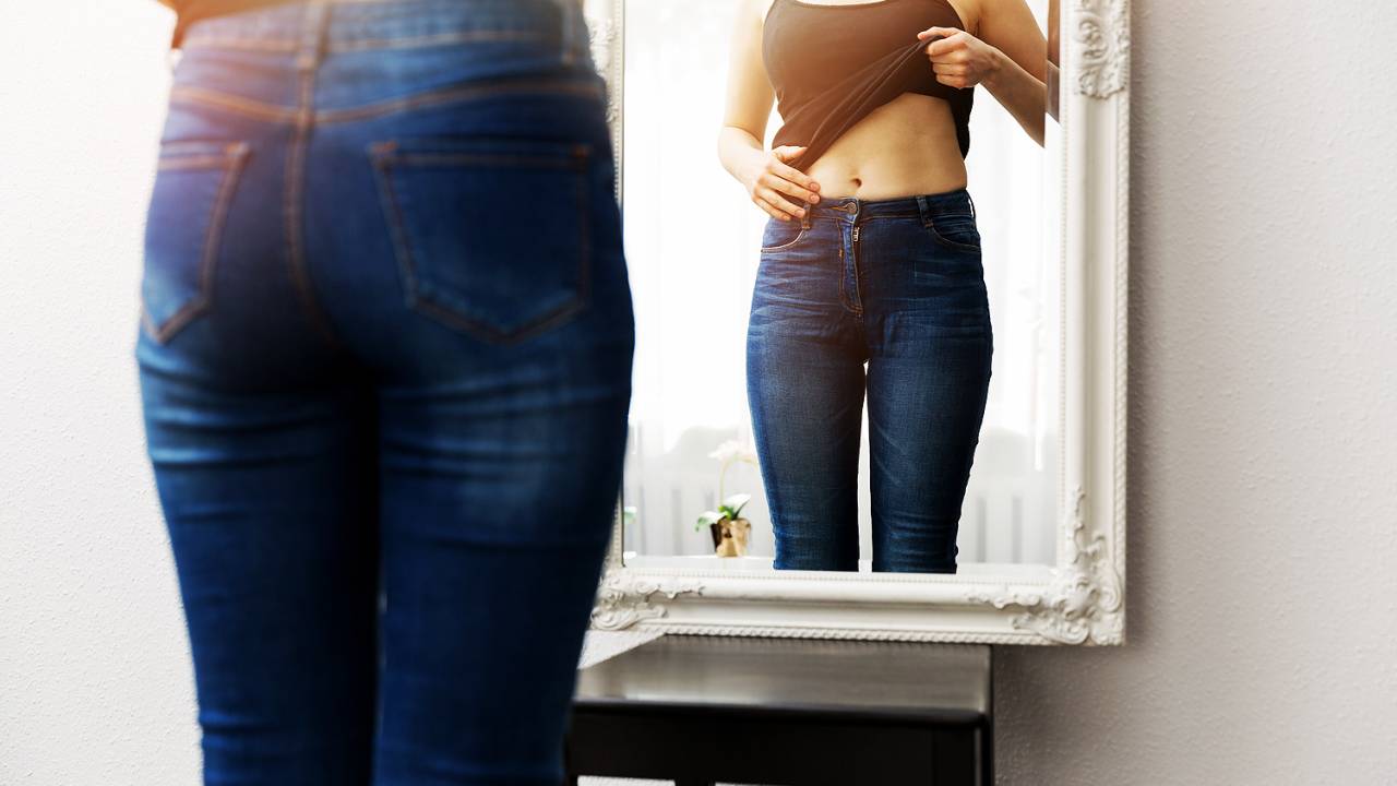 Mulher, verificando seu corpo na frente do espelho