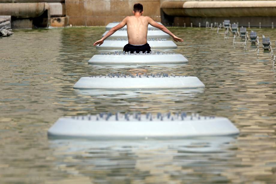 Homem se refresca do calor em uma fonte pública no centro de Paris, na França - 22/06/2017