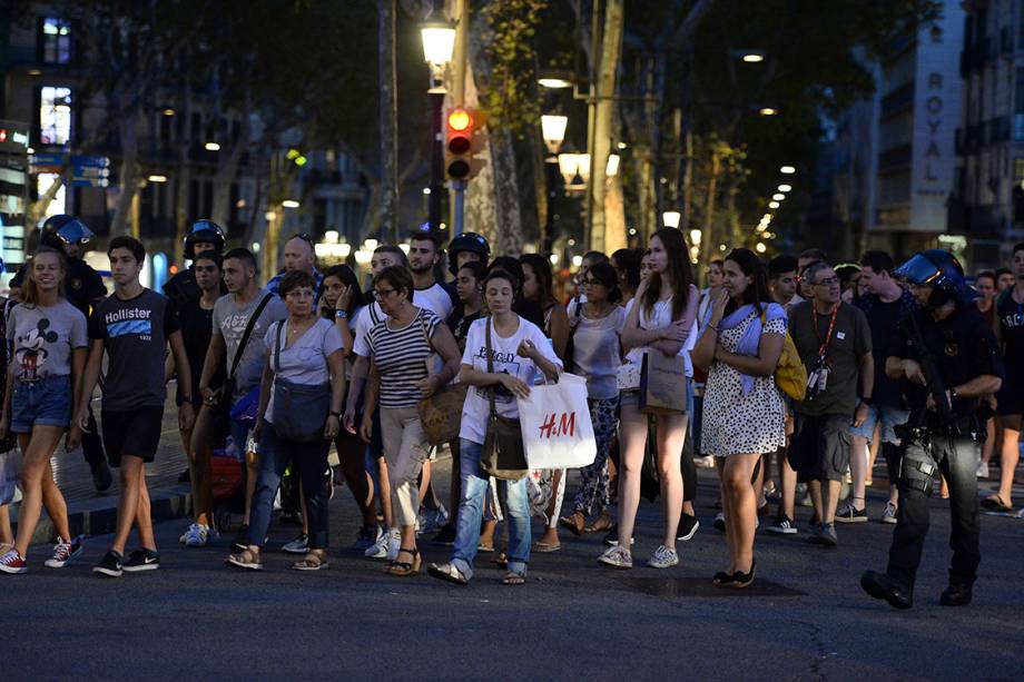 Policiais acompanham clientes de uma loja para fora da área isolada após atropelamento em La Rambla, em Barcelona