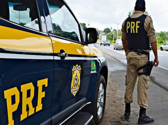 .Agente da PRF observa a rodovia ao lado de sua viatura