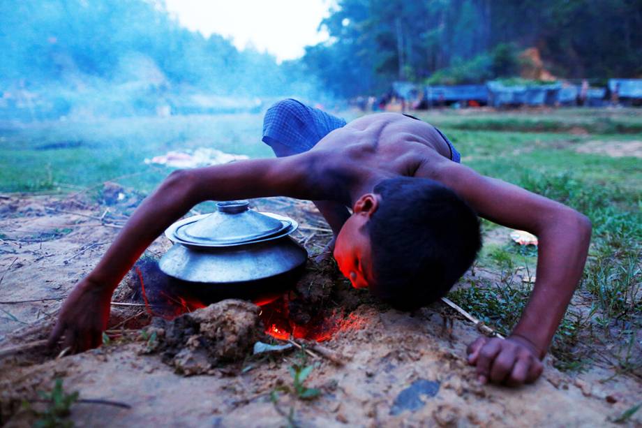 Criança refugiada acende fogo para cozinhar uma refeição, próximo ao seu abrigo temporário - 12/09/2017