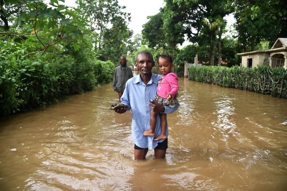 Homem carrega uma criança em uma rua inundada na cidade de Fort Liberte, no nordeste do Haiti durante a passagem do furacão Irma - 08/09/2017