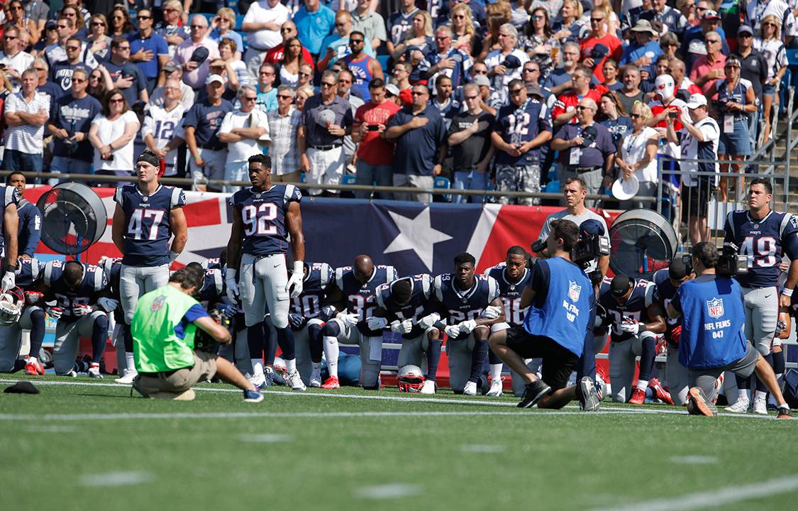 Jogadores do New England Patriots ficam de braços dados durante hino nacional que antecede a partida em forma de protesto contra Donald Trump, que defendeu a demissão de jogadores que protestassem em campo