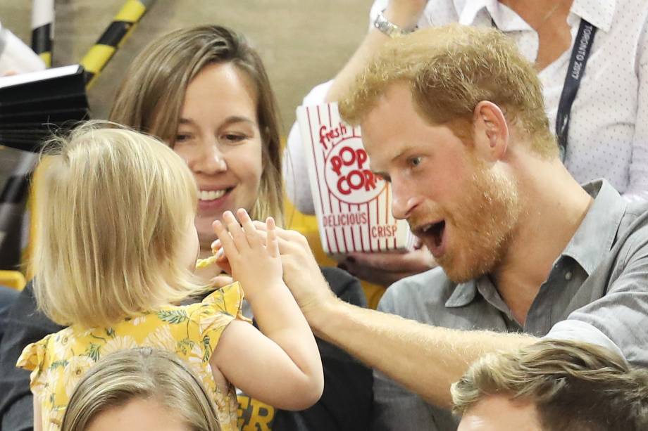 Hayley Henson e a filha Emily Henson sentam-se com o Príncipe Harry para comer pipoca e assistir às finais do vôlei durante os Jogos Invictus 2017 no Centro de Atletismo Mattamy, em Toronto, no Canadá