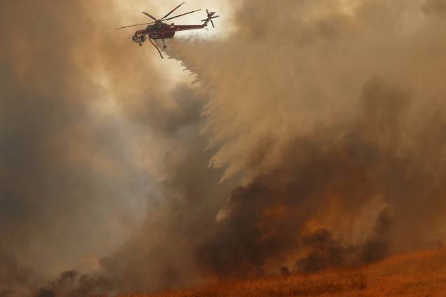 Um helicóptero do corpo de bombeiros derrama água na tentativa de conter o incêndio florestal que atingiu a cidade de Orange, no estado norte-americano da Califórnia - 09/10/2017 Um helicóptero do corpo de bombeiros derrama água na tentativa de conter o incêndio florestal que atingiu a cidade de Orange, no estado norte-americano da Califórnia - 09/10/2017