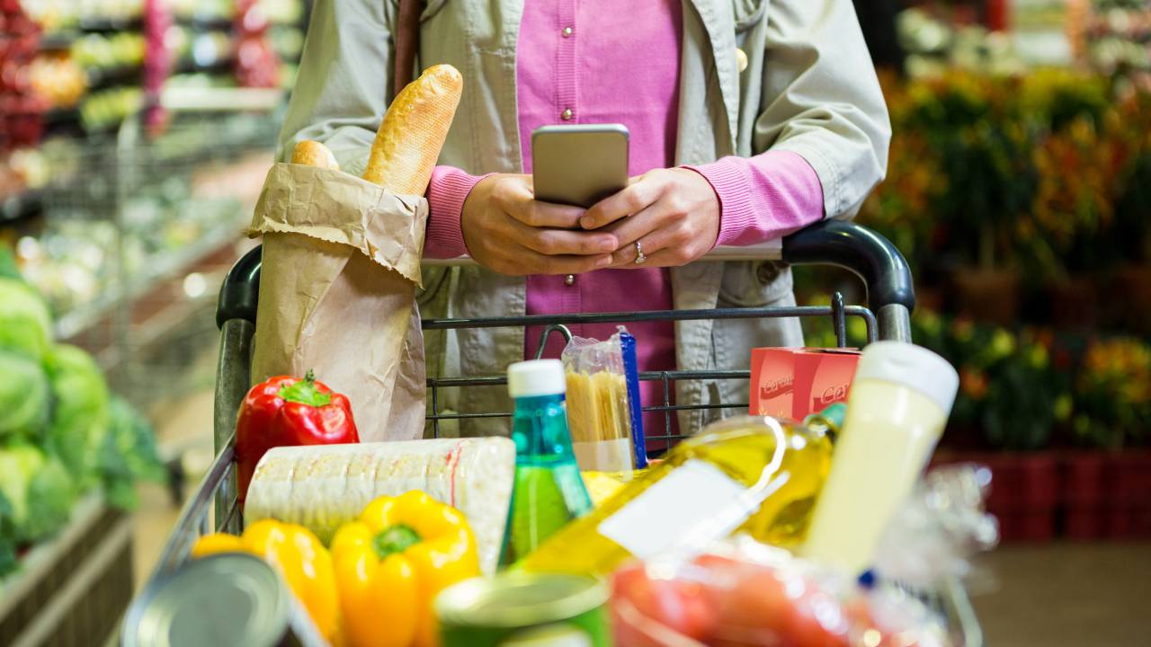 Mulher mexendo no celular enquanto faz compras