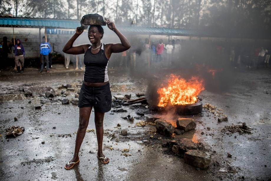 Manifestantes de oposição protestam sob a forte chuva em frente a uma barricada no distrito de Mathare, em Nairóbi. Um grupo de manifestantes bloqueou a estrada e tentou evitar que os eleitores acessassem uma mesa de voto durante eleições presidenciais - 26/10/2017