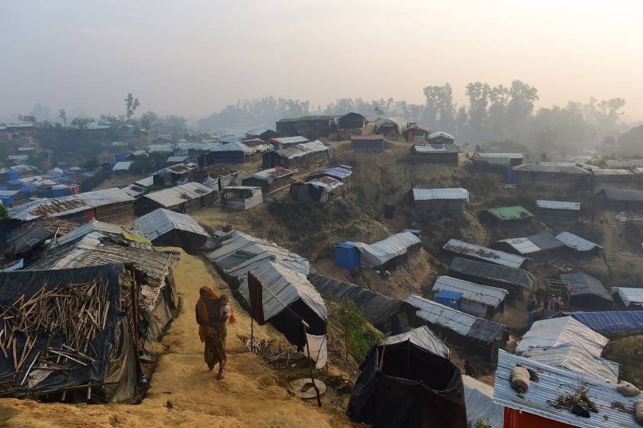 Mulher caminha com uma criança no colo no campo de refugiados de Balukhali, no distrito bengali de Ukhia - 23/11/2017