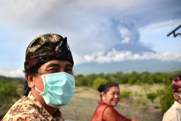 Balineses passam em frente ao Monte Agung durante uma erupção vista do subdistrito de Kubu em Karangasem Regency, na ilha turística de Bali, na Indoésia - 27/11/2017 Balineses passam em frente ao Monte Agung durante uma erupção vista do subdistrito de Kubu em Karangasem Regency, na ilha turística de Bali, na Indoésia - 27/11/2017