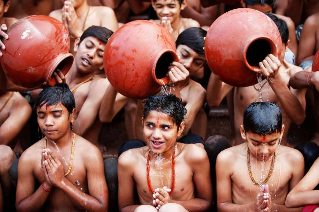 Estudantes tomam banho sagrado através de jarros de barro, durante cerimônia religiosa realizada no mês hindu de Magh, em Ahmedabad, na Índia - 01/01/2018