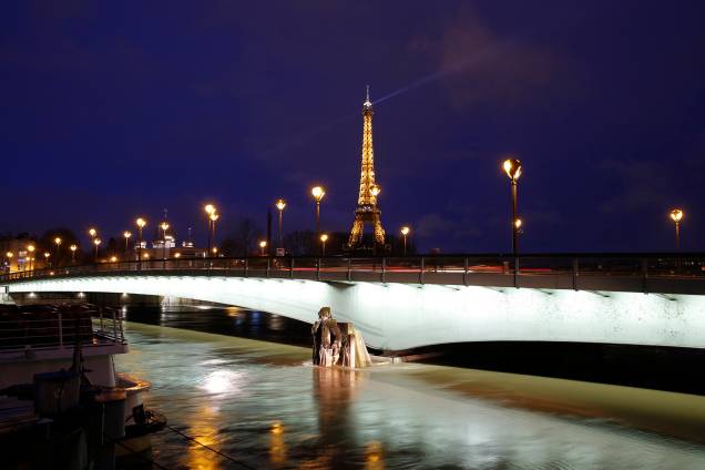 Torre Eiffel iluminada, ao lado do rio Sena, com níveis de água elevados cobrindo a estátua Zouave na ponte Pont d'Alma, em Paris - 25/01/2018 Torre Eiffel iluminada, ao lado do rio Sena, com níveis de água elevados cobrindo a estátua Zouave na ponte Pont d'Alma, em Paris - 25/01/2018