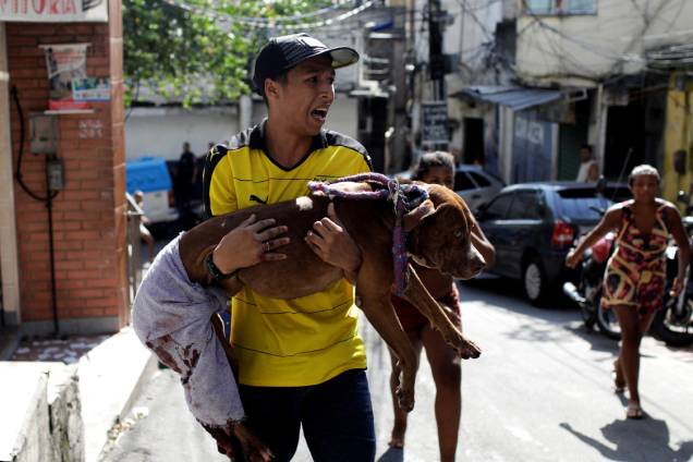 Homem carrega seu cachorro, que segundo ele foi baleado durante tiroteio entre policiais e traficantes na comunidade da Rocinha, no Rio de Janeiro - 25/01/2018 Homem carrega seu cachorro, que segundo ele foi baleado durante tiroteio entre policiais e traficantes na comunidade da Rocinha, no Rio de Janeiro - 25/01/2018