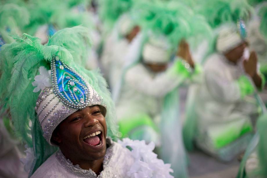 Integrantes da escola de samba Mocidade Indepentende desfilam à medida que o sol nasce após a primeira noite do Carnaval na Marquês de Sapucaí - 12/02/2018