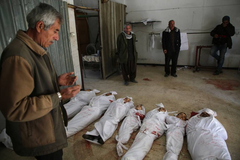 Homem faz orações ao lado de corpos preparados para o o funeral de vítimas civis mortas durante ataques aéreos do governo na cidade rebelde de Arbin, na região sitiada de Ghouta Oriental - 20/02/2018