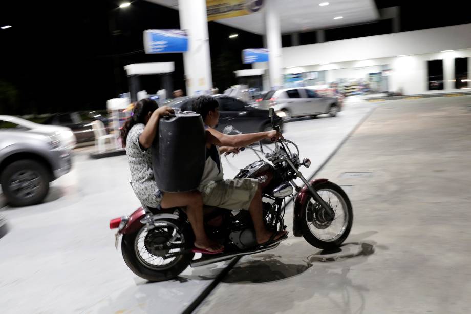 Mulher deixa um posto de combustível carregando galão de gasolina sobre uma moto em Manaus (AM) - 25/05/2018 Mulher deixa um posto de combustível carregando galão de gasolina sobre uma moto em Manaus (AM) - 25/05/2018