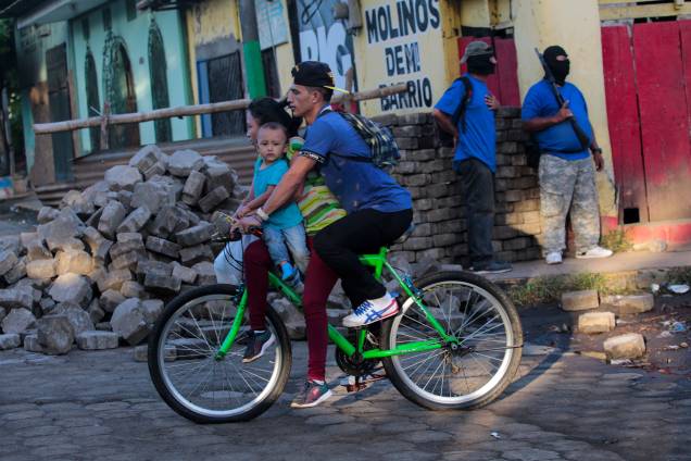 Família passa de bicicleta por manifestantes pró-governo após confrontos na comunidade indígena de Monimbo, em Masaya, Nicarágua - 17/07/2018 Família passa de bicicleta por manifestantes pró-governo após confrontos na comunidade indígena de Monimbo, em Masaya, Nicarágua - 17/07/2018