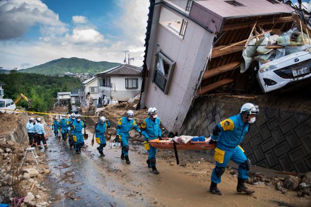 Policiais chegam para trabalhar no resgate de vítimas e retirada de destroços espalhados em uma rua destruída após inundações em Kumano, prefeitura de Hiroshima, no Japão - 09/07/2018 Policiais chegam para trabalhar no resgate de vítimas e retirada de destroços espalhados em uma rua destruída após inundações em Kumano, prefeitura de Hiroshima, no Japão - 09/07/2018