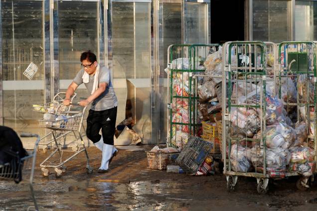 Funcionário de um supermercado empurra um carrinho, com itens enlameados, em uma área inundada na cidade de Mabi em Kurashiki, prefeitura de Okayama, no Japão - 09/07/2018 Funcionário de um supermercado empurra um carrinho, com itens enlameados, em uma área inundada na cidade de Mabi em Kurashiki, prefeitura de Okayama, no Japão - 09/07/2018