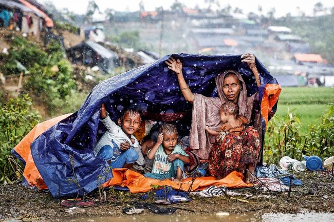 Família de rohingyas protege-se da chuva, em Bangladesh: refúgio no país vizinho.