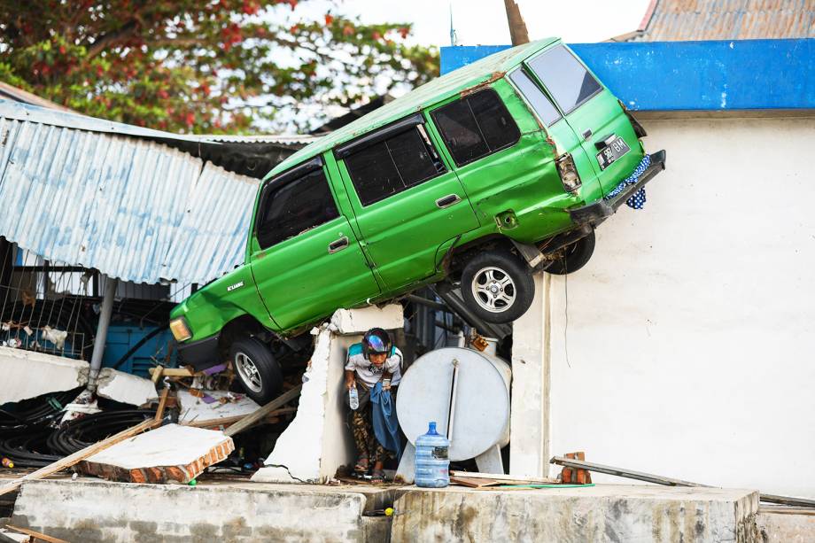 Sobrevivente caminha debaixo de carro após terremoto seguido de tsunami atingir a região de Palu, na Indonésia - 01/10/2018