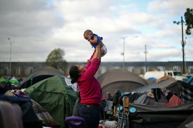 Migrante ergue bebê em acampamento montado na fronteira entre o México e os Estados Unidos, na cidade de Tijuana - 28/11/2018 Migrante ergue bebê em acampamento montado na fronteira entre o México e os Estados Unidos, na cidade de Tijuana - 28/11/2018