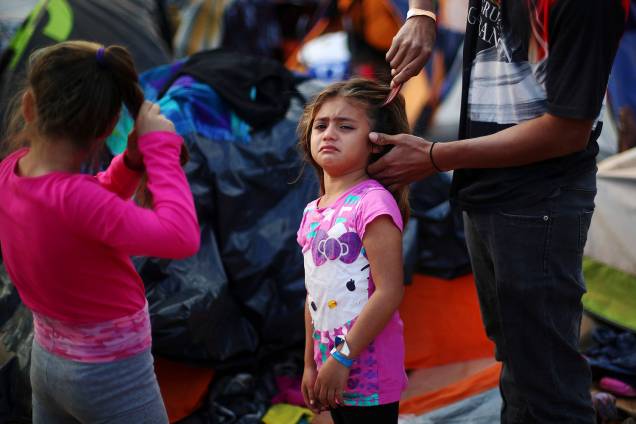 Garota chora enquanto seu pai escova seu cabelo em acampamento improvisado, montado por membros da caravana de imigrantes da América Central, nos arredores da fronteira entre o México e os Estados Unidos, na cidade de Tijuana - 28/11/2018 Garota chora enquanto seu pai escova seu cabelo em acampamento improvisado, montado por membros da caravana de imigrantes da América Central, nos arredores da fronteira entre o México e os Estados Unidos, na cidade de Tijuana - 28/11/2018