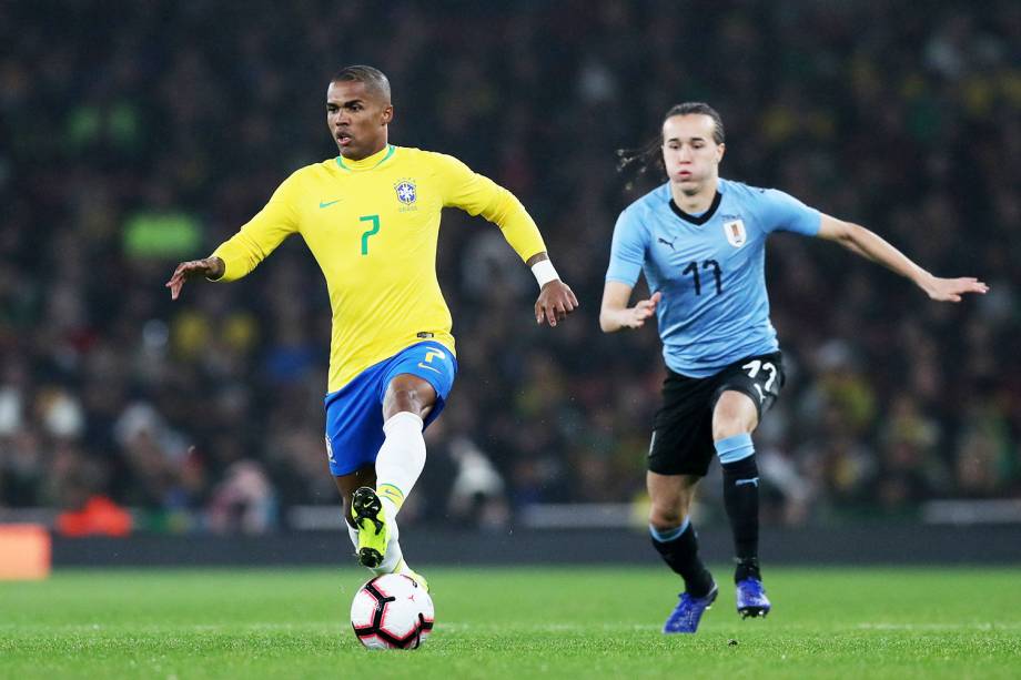 Douglas Costa (esq) disputa bola com Diego Laxalt (dir), durante amistoso entre Brasil e Uruguai, realizado no Emirates Stadium, em Londres - 16/11/2018