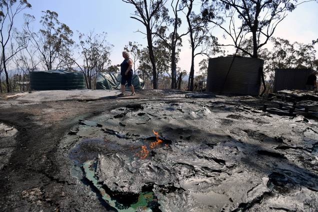 Jeanette Schwindt, residente local, inspeciona seu galpão e tanques de água destruídos depois que um incêndio florestal varreu a área no Monte Larcom em Queensland, Austrália - 29/11/2018 Jeanette Schwindt, residente local, inspeciona seu galpão e tanques de água destruídos depois que um incêndio florestal varreu a área no Monte Larcom em Queensland, Austrália - 29/11/2018