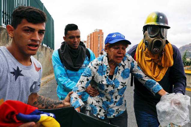 Manifestantes se protegem de bombas de gás lacrimogêneo lançadas por policiais, durante marcha contra o presidente venezuelano Nicolás Maduro, em Caracas - 23/01/2019 Manifestantes se protegem de bombas de gás lacrimogêneo lançadas por policiais, durante marcha contra o presidente venezuelano Nicolás Maduro, em Caracas - 23/01/2019