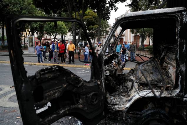 Pessoas observam um caminhão que foi queimado durante os protestos contra o governo de Nicolas Maduro em Caracas, Venezuela - 24/01/2019 Pessoas observam um caminhão que foi queimado durante os protestos contra o governo de Nicolas Maduro em Caracas, Venezuela - 24/01/2019