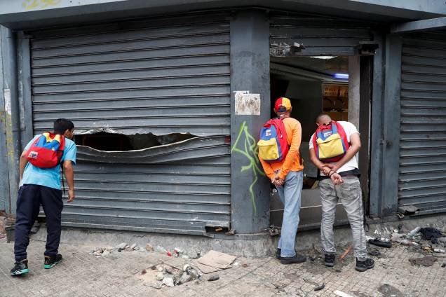 Homens olham dentro de uma loja de liquor saqueada após os protestos contra o governo de Nicolas Maduro em Caracas, na Venezuela - 24/01/2019 Homens olham dentro de uma loja de liquor saqueada após os protestos contra o governo de Nicolas Maduro em Caracas, na Venezuela - 24/01/2019