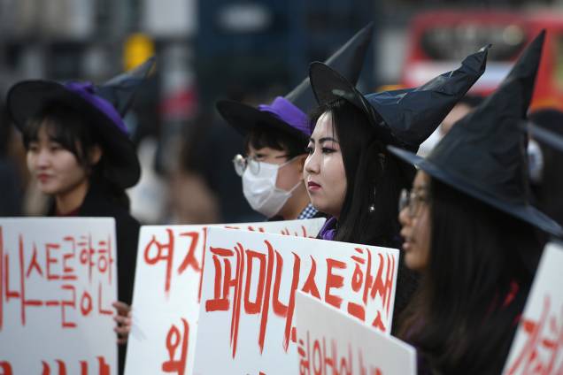 Mulheres sul-coreanas vestidas de bruxa seguram cartazes apoiando o feminismo durante um protesto para marcar o Dia Internacional da Mulher em Seul - 08/03/2019 Mulheres sul-coreanas vestidas de bruxa seguram cartazes apoiando o feminismo durante um protesto para marcar o Dia Internacional da Mulher em Seul - 08/03/2019