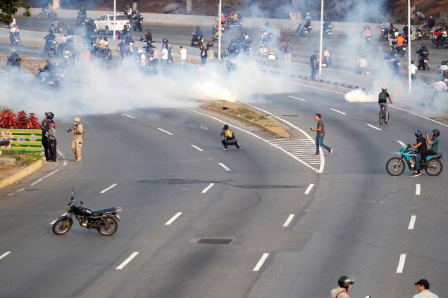 Pessoas reagem ao gás lacrimogêneo durante confrontos nos arredores da base aérea "La Carlota", em Caracas, Venezuela - 30/04/2019 Pessoas reagem ao gás lacrimogêneo durante confrontos nos arredores da base aérea "La Carlota", em Caracas, Venezuela - 30/04/2019