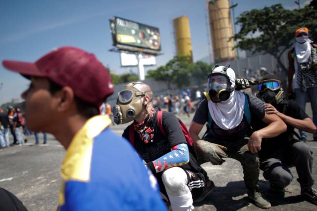 Manifestantes de oposição usam máscaras de gás para se proteger dos ataques das forças leais a Nicolás Maduro durante confrontos nos arredores da base aérea La Carlota em Caracas, na Venezuela - 30/04/2019 Manifestantes de oposição usam máscaras de gás para se proteger dos ataques das forças leais a Nicolás Maduro durante confrontos nos arredores da base aérea La Carlota em Caracas, na Venezuela - 30/04/2019