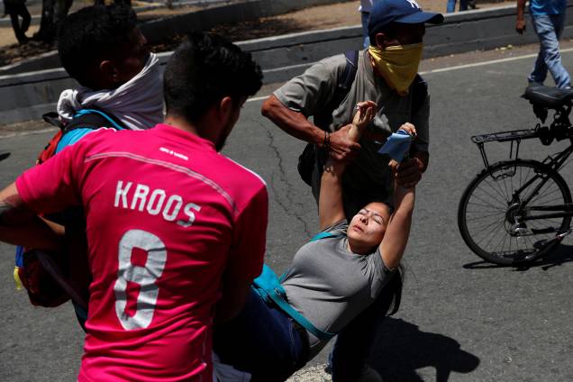 Manifestantes carregam uma mulher ferida durante confrontos com forças leais a Nicolás Maduro nos arredores da base aérea de La Carlota em Caracas, na Venezuela - 30/04/2019 Manifestantes carregam uma mulher ferida durante confrontos com forças leais a Nicolás Maduro nos arredores da base aérea de La Carlota em Caracas, na Venezuela - 30/04/2019