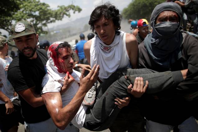 Manifestante ferido é carregado após ser atropelado por um veículo da Guarda Nacional Bolivariana nos arredores da base aérea La Carlota em Caracas, na Venezuela - 30/04/2019 Manifestante ferido é carregado após ser atropelado por um veículo da Guarda Nacional Bolivariana nos arredores da base aérea La Carlota em Caracas, na Venezuela - 30/04/2019