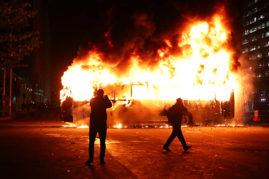 Pessoas tiram fotos de ônibus incendiado durante protesto contra o corte de verba nas universidades federais, no Rio de Janeiro (RJ) - 15/05/2019