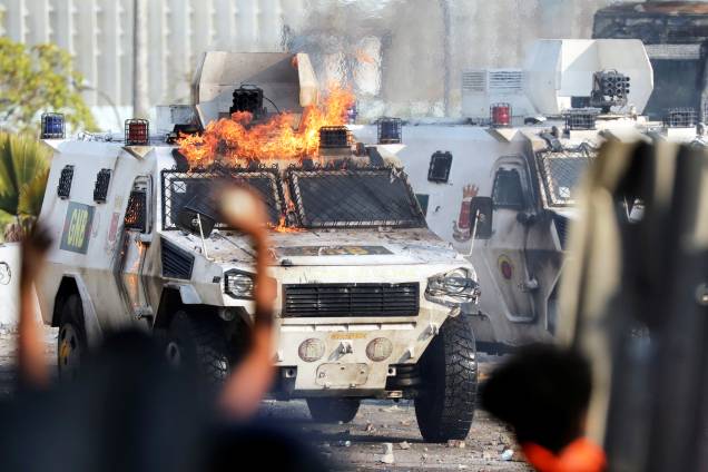 Manifestantes colocam fogo em veículo militar durante confronto em Caracas, capital da Venezuela - 01/05/2019 Manifestantes colocam fogo em veículo militar durante confronto em Caracas, capital da Venezuela - 01/05/2019