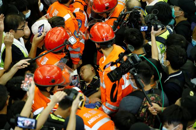 Medics attempt to remove an injured man who anti-government protesters said was an undercover policeman at the airport in Hong Kong Medics attempt to remove an injured man who anti-government protesters said was an undercover policeman at the airport in Hong Kong