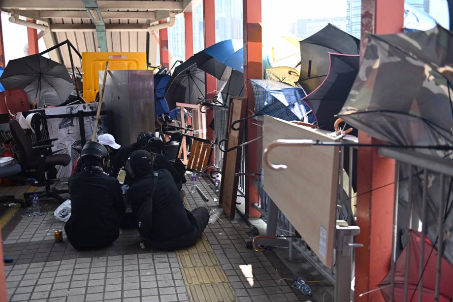 Manifestantes são vistos sentados em uma passarela barricada dentro da Universidade Politécnica no distrito de Tsim Sha Tusi durante um protesto antigovernamental em Hong Kong, China