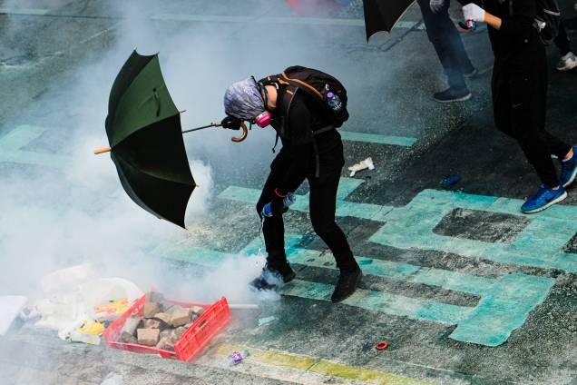 Um manifestante coloca água em uma lata de gás lacrimogêneo durante a manifestação em Hong Kong Um manifestante coloca água em uma lata de gás lacrimogêneo durante a manifestação em Hong Kong
