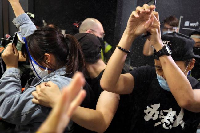 Anti-government protesters react as riot police disperse them with pepper spray during a rally inside a shopping mall, in Hong Kong Anti-government protesters react as riot police disperse them with pepper spray during a rally inside a shopping mall, in Hong Kong